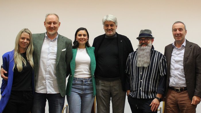 Zukunft des Friseurhandwerks im Fokus: Jahresversammlung 2024 Sechs Menschen stehen nebeneinander vor einer weißen Wand und lächeln