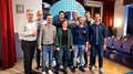 Rittner Musterschau verbindet Menschen und Ideen Neun Personen posieren in einem Raum mit Stühlen und rotem Vorhang für ein Gruppenfoto