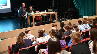 News Zwei Frauen sprechen vor einem Publikum von Jugendlichen in einem Theater