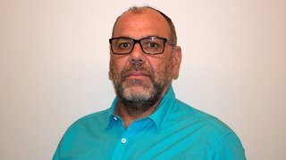 News Porträt eines Mannes mit Brille und blauem Hemd vor weißem Hintergrund