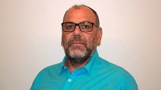 News Porträt eines Mannes mit Brille und blauem Hemd vor weißem Hintergrund