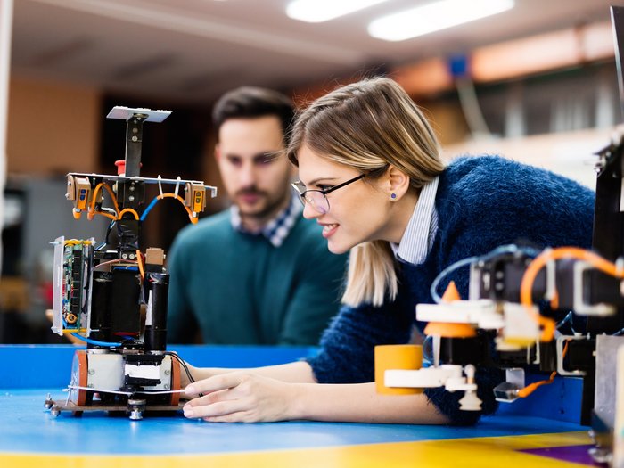 Neue Beiträge für Unternehmen, die weibliche Lehrlinge in MINT-Berufen beschäftigen Frau und Mann prüfen Roboter in einer Technikwerkstatt