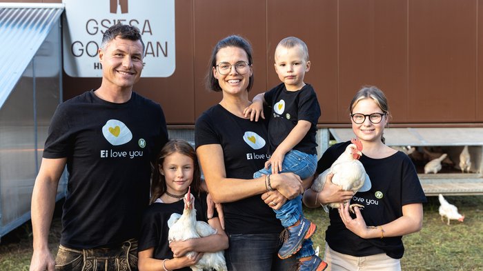 © Südtiroler Bauernbund Familie mit Hühnern vor Hühnerstall trägt schwarze Ei love you T-Shirts
