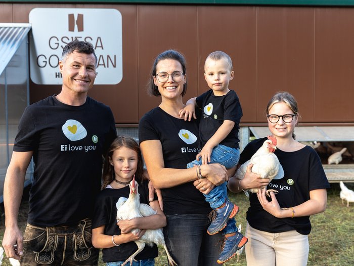 © Südtiroler Bauernbund Familie mit Hühnern vor Hühnerstall trägt schwarze Ei love you T-Shirts