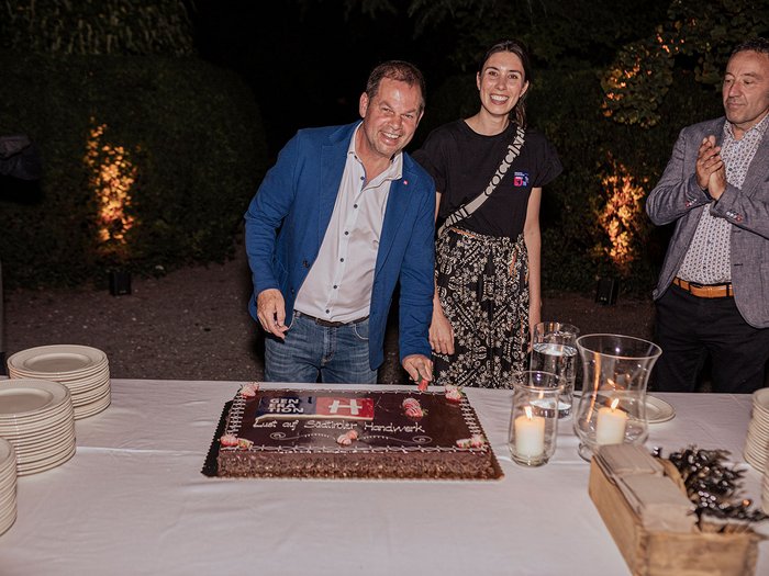 Generation-H Aperitif Mann schneidet Kuchen bei Abendfeier mit zwei weiteren Personen