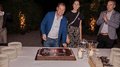 Generation-H Aperitif Mann schneidet Kuchen bei Abendfeier mit zwei weiteren Personen