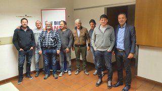 News Acht Männer stehen in einem Raum und posieren für ein Gruppenfoto