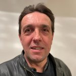 Unterpustertal/Gadertal Porträt eines lächelnden Mannes mit Lederjacke vor weißem Hintergrund