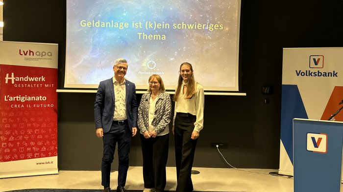 Geldanlage ist (k)ein Thema – Frauen im Handwerk setzen auf finanzielle Kompetenz Drei Personen stehen vor einer Leinwand mit Vortrag zu Geldanlage und Bankenbanner