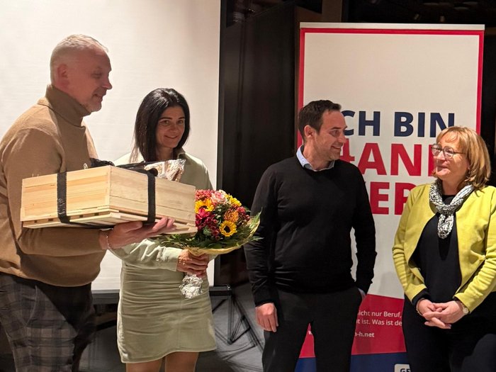 Handwerk mit Haltung – Rückblick und Aufbruch im Wipptal Vier Personen bei einer Zeremonie mit Blumen und Geschenk im Innenraum