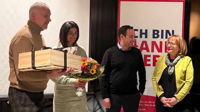 Handwerk mit Haltung – Rückblick und Aufbruch im Wipptal Vier Personen bei einer Zeremonie mit Blumen und Geschenk im Innenraum