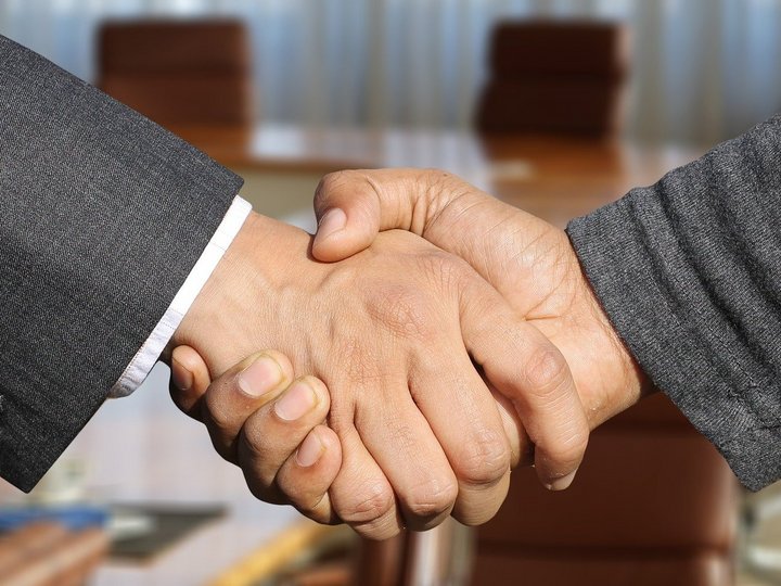 Fakten zum Thema Zwei Personen geben sich die Hand in einem Büro