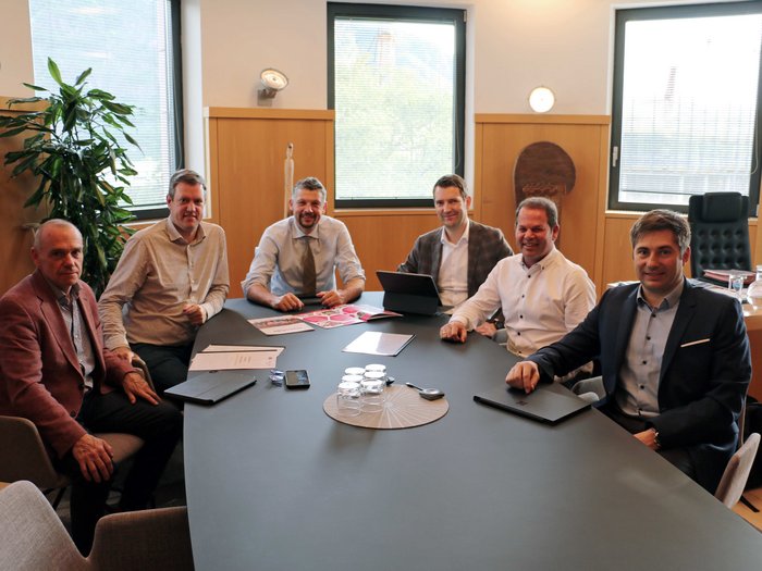 Confronto con il consigliere provinciale Daniel Alfreider: focus sulle soluzioni di mobilità intelligente per il futuro Sei uomini seduti a un tavolo da conferenza in un ufficio con finestre e piante