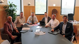 News Sechs Männer sitzen an einem Konferenztisch in einem Büro mit Fenstern und Pflanzen