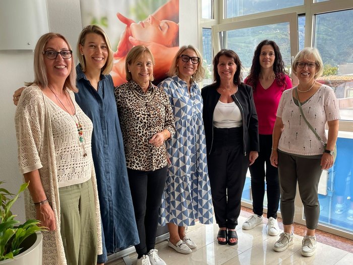 Frauen entdecken Traditionsbetriebe Sieben lächelnde Frauen stehen nebeneinander in einem hellen Raum vor einem Fenster.