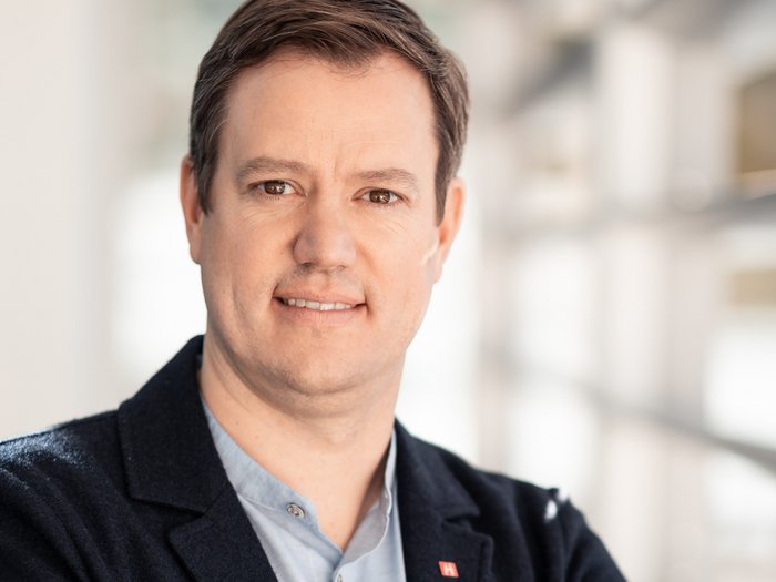 lvh-Präsident Martin Haller, Foto: ©Florian Andergassen Porträt eines Mannes im Blazer mit verschränkten Armen in einem modernen Gebäude.