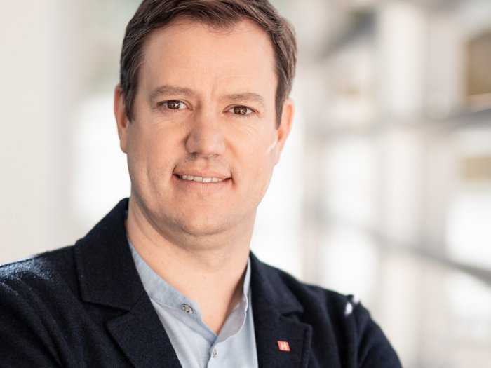 lvh-Präsident Martin Haller, Foto: ©Florian Andergassen Porträt eines Mannes im Blazer mit verschränkten Armen in einem modernen Gebäude.