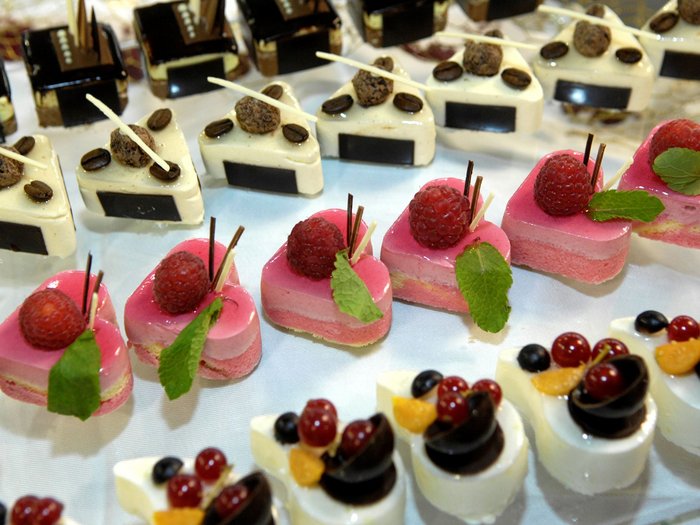 Muttertag: Geschenke für Superheldinnen Verschiedene kleine, kunstvoll dekorierte Dessertstücke auf weißem Tisch