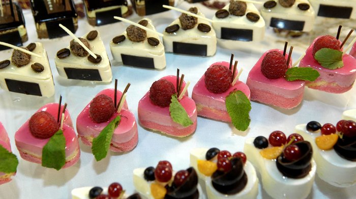 Muttertag: Geschenke für Superheldinnen Verschiedene kleine, kunstvoll dekorierte Dessertstücke auf weißem Tisch