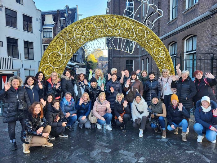 Le donne nell’artigianato sulle tracce di van Gogh Gruppo di persone che sorridono e salutano davanti a un arco decorativo