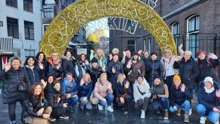 News Gruppe von Menschen posiert lachend und winkend vor einem dekorativen Torbogen