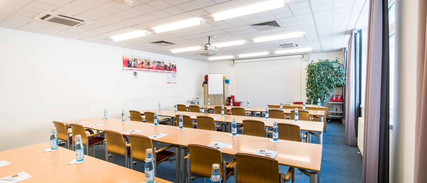 Vermietung Seminarräume Konferenzraum mit Tischen, Stühlen, Flaschen und Schreibmaterialien