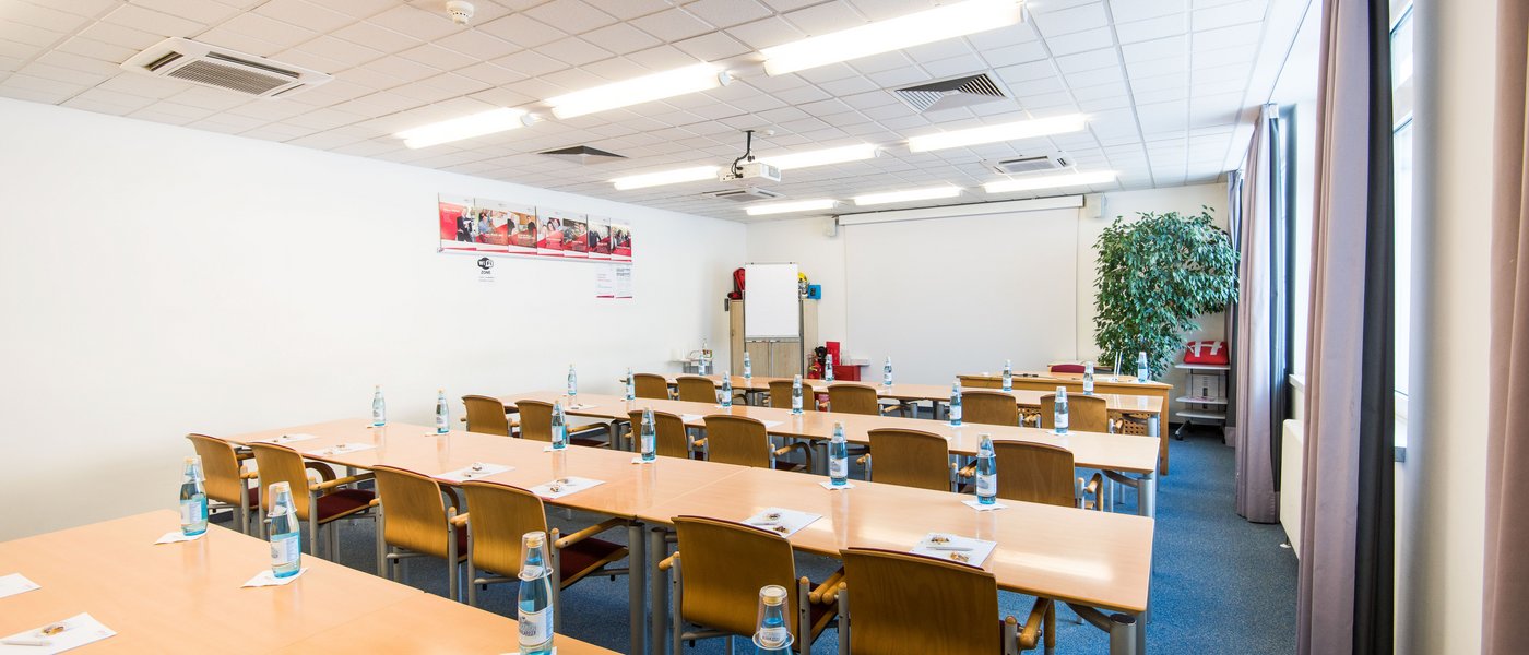 Affitto aule seminari Sala conferenze con tavoli, sedie, bottiglie e materiali per scrivere