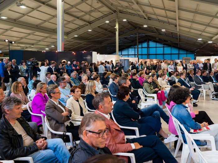 La 31^ Fiera d’Arte UNIKA apre le porte a Ortisei Grande pubblico seduto e in piedi durante un evento in un capannone