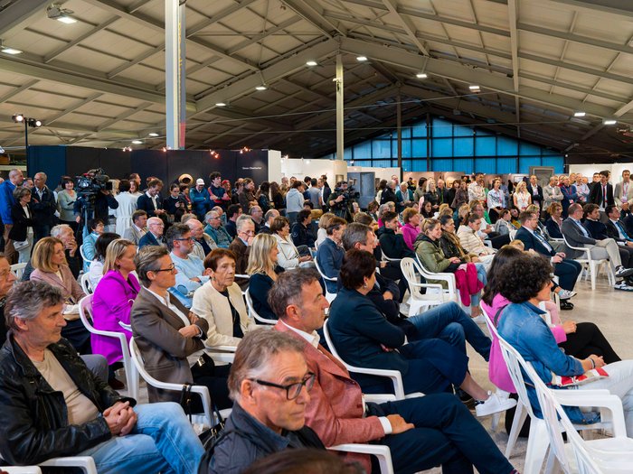 Die 31. UNIKA-Kunstmesse eröffnet in St. Ulrich Große versammelte Zuhörerschaft bei einer Veranstaltung in einer Halle