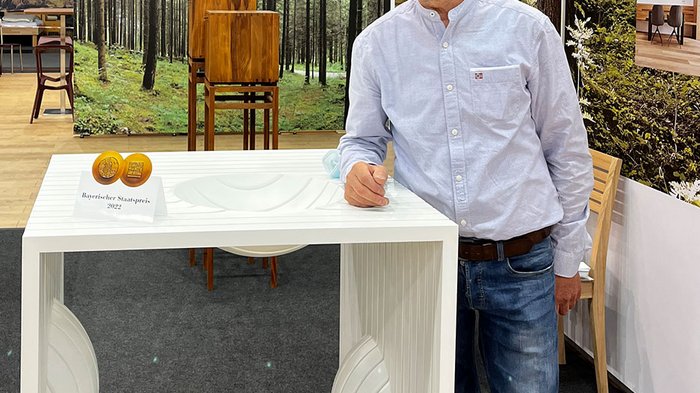 IHM: aziende altoatesine protagoniste Uomo presenta tavolo moderno bianco con premio statale bavarese alla fiera