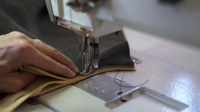 Ein Abend im Zeichen des Handwerks Hand führt Leder durch eine Nähmaschine beim Nähen