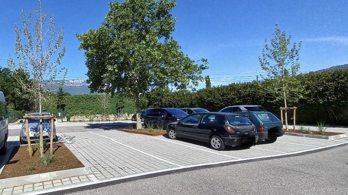 Flächenverbrauch auf Rekordhöhe in Italien – auch in Südtirol anhaltender Anstieg Parkplatz mit mehreren geparkten Autos und Bäumen unter klarem blauen Himmel
