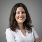 Soluzioni digitali Donna sorridente con capelli castani e camicia bianca su sfondo grigio