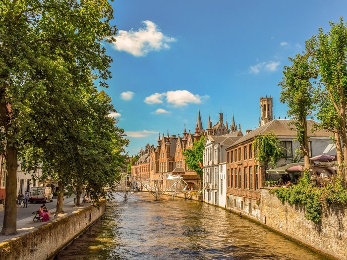 Althandwerker/innen im Herzen der Europäischen Union Historische Gebäude entlang eines Kanals in einer sonnigen Stadt mit Bäumen
