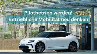 News Weißes Elektroauto an Ladesäule unter Dach im urbanen Umfeld