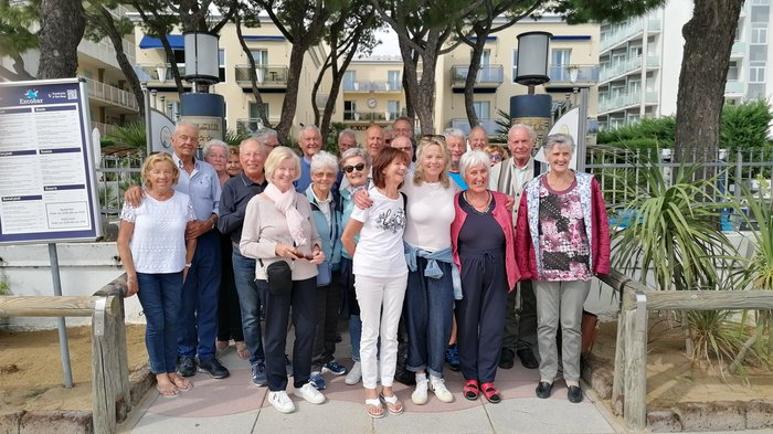 Badespaß an der Adria Gruppe älterer Menschen steht zusammen draußen vor Bäumen und Gebäuden