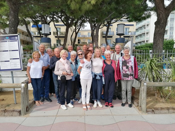 Badespaß an der Adria Gruppe älterer Menschen steht zusammen draußen vor Bäumen und Gebäuden