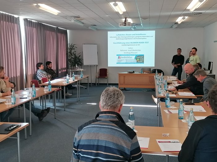 Aktivitäten der Hafner/innen im lvh Seminarraum mit Teilnehmern, die einer Präsentation zum Blower-Door-Test folgen