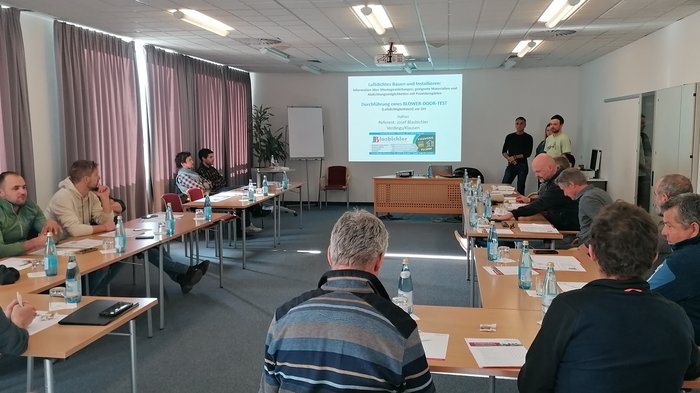 Aktivitäten der Hafner/innen im lvh Seminarraum mit Teilnehmern, die einer Präsentation zum Blower-Door-Test folgen