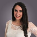 Stefanie Röll Ritratto di donna sorridente con capelli lunghi e scuri e camicetta bianca in pizzo su sfondo grigio