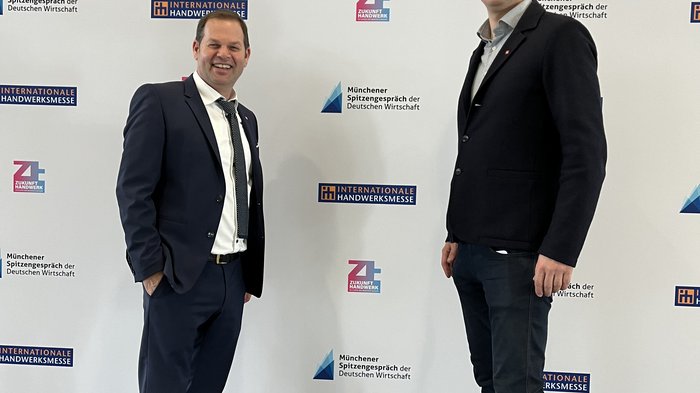 Una delegazione sudtirolese visita la fiera bavarese "Zukunft Handwerk" Due uomini in abito davanti al muro con scritto Münchener Spitzengespräch der Deutschen Wirtschaft