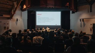 News Publikum hört Vortrag bei einer Wirtschaftsschau in einem dunklen Saal