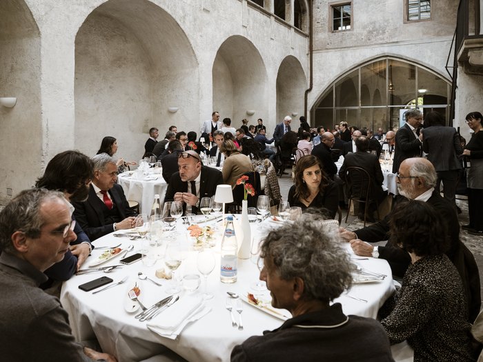 10 Jahre Sani-Fonds Menschen bei formellem Mittagessen in historischem Innenhof mit Rundbögen