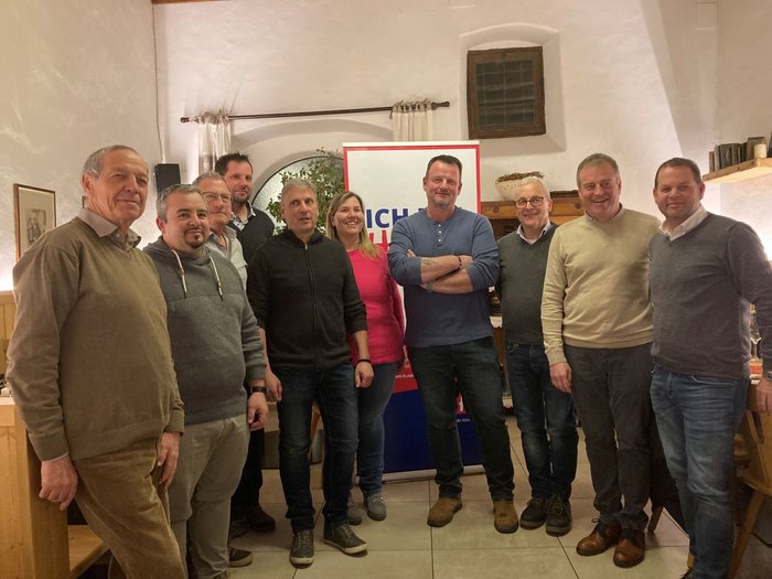 Viel Schwung unter den Handwerker/innen Zehn Personen stehen in einem Raum vor einem Schild und lächeln