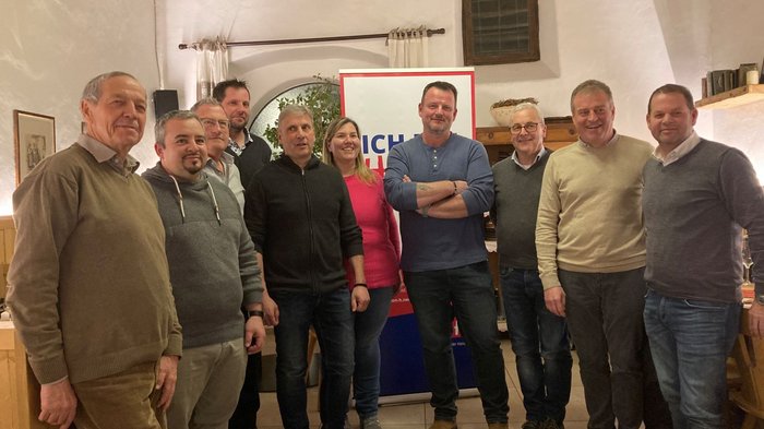 Viel Schwung unter den Handwerker/innen Zehn Personen stehen in einem Raum vor einem Schild und lächeln