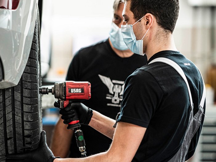 Sicher unterwegs mit Winterreifen Zwei Mechaniker wechseln Reifen eines Autos in Werkstatt