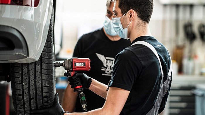 Sicher unterwegs mit Winterreifen Zwei Mechaniker wechseln Reifen eines Autos in Werkstatt