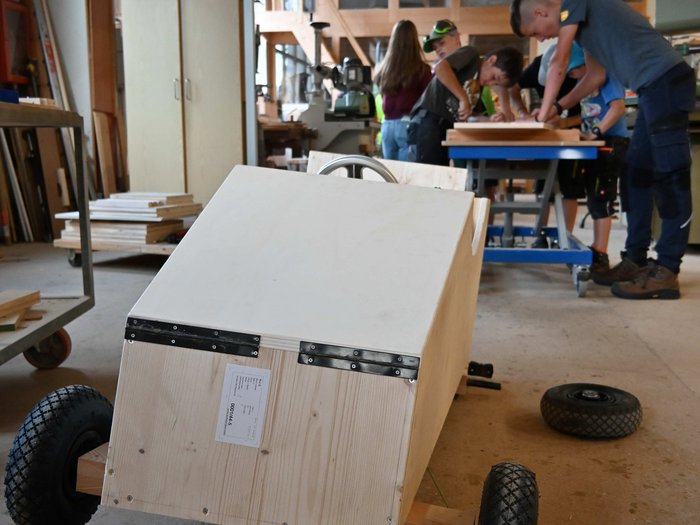 Gara di Soapbox a San Felice: l'artigianato corre veloce Macchina di legno in officina con adolescenti che lavorano sullo sfondo