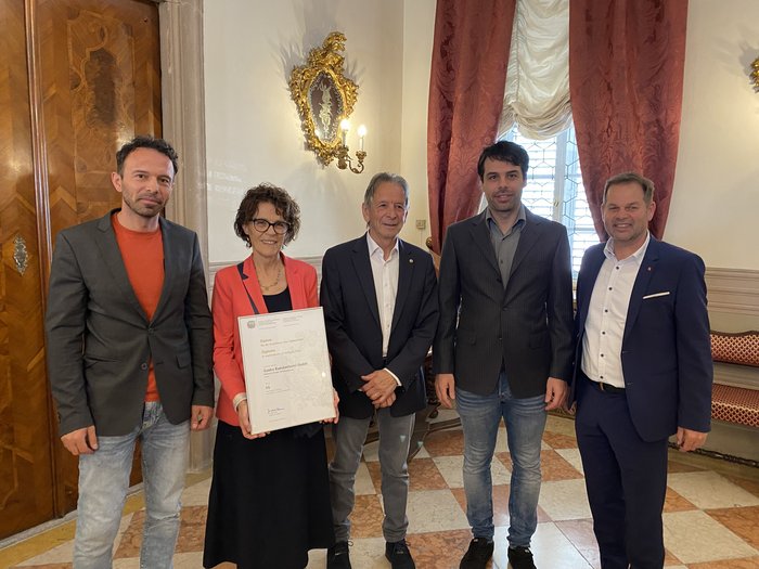 Consegna del premio Economia Alto Adige 2025 Cinque persone in abiti formali, una tiene un premio in un ambiente elegante