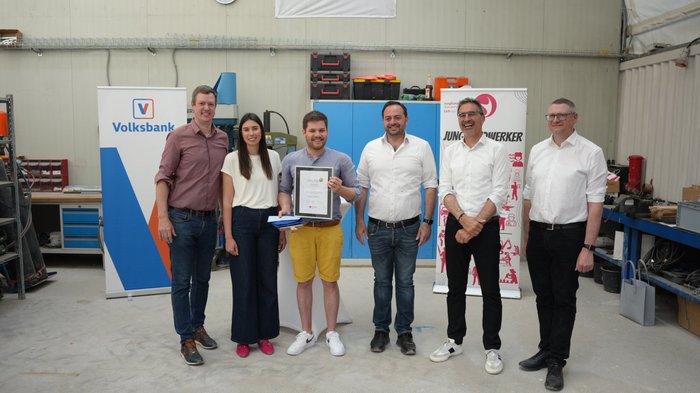 Junghandwerker/innen des Jahres gekürt Sechs Personen stehen in Werkstatt, eine hält eine Urkunde, Banner im Hintergrund